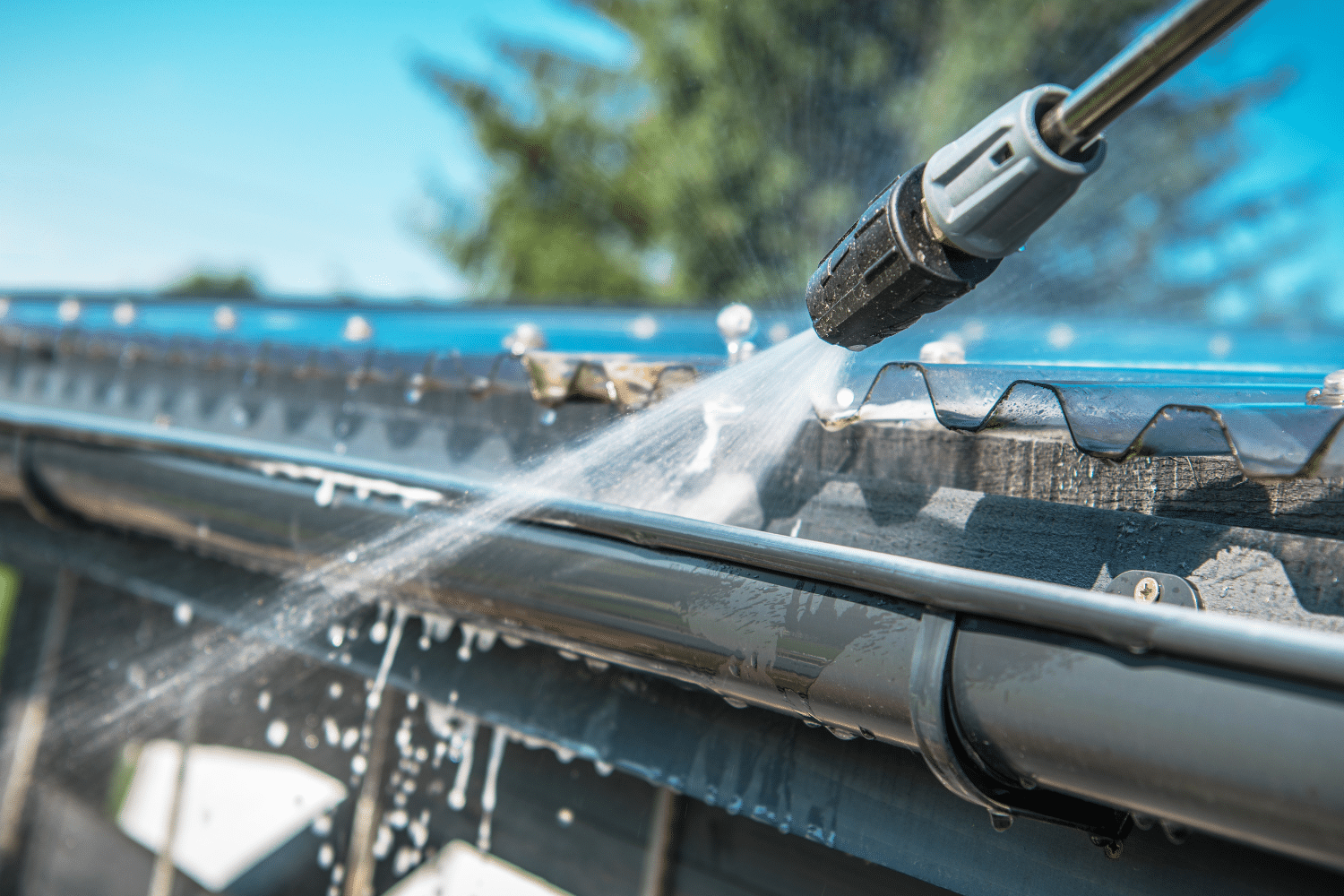 Cleaning gutters with a garden hose to prevent clogs
