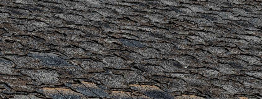 The image displays a roof covered with asphalt shingles, which appear to be worn and potentially damaged