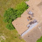 The image displays a roof with significant damage, specifically showing missing and damaged shingles