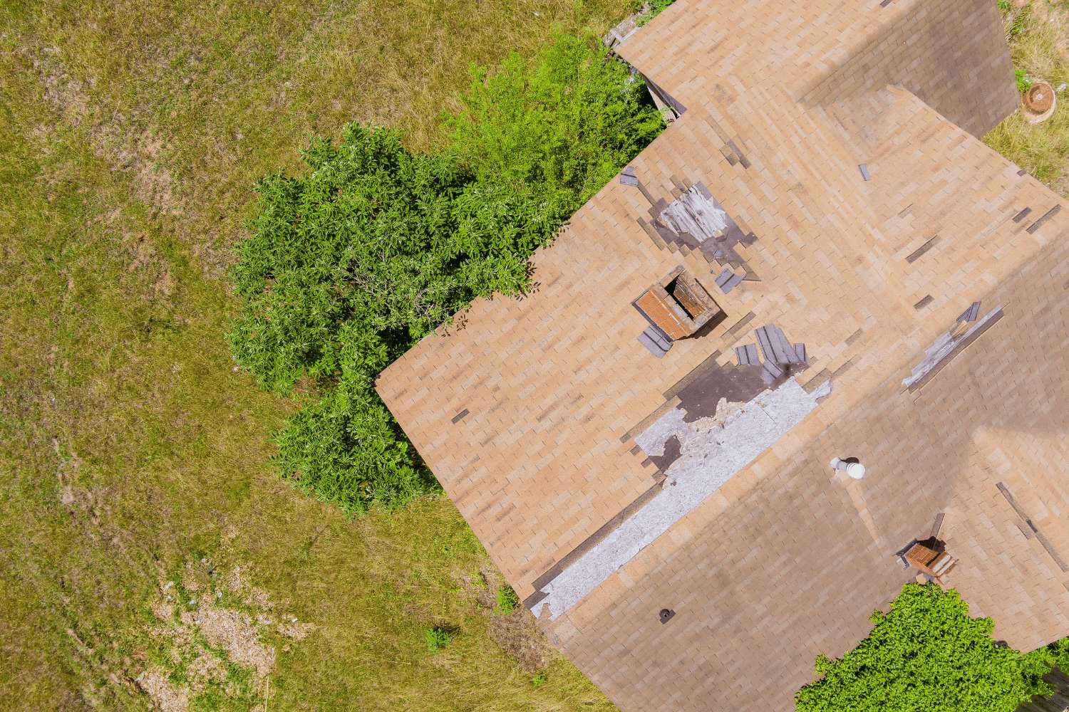 The image displays a roof with significant damage, specifically showing missing and damaged shingles